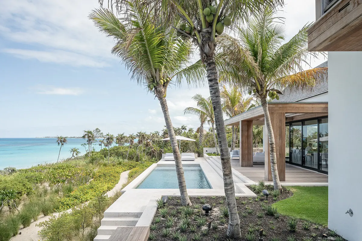 Exterior area with swimming pool, palm trees, lounge chairs, and beach view.