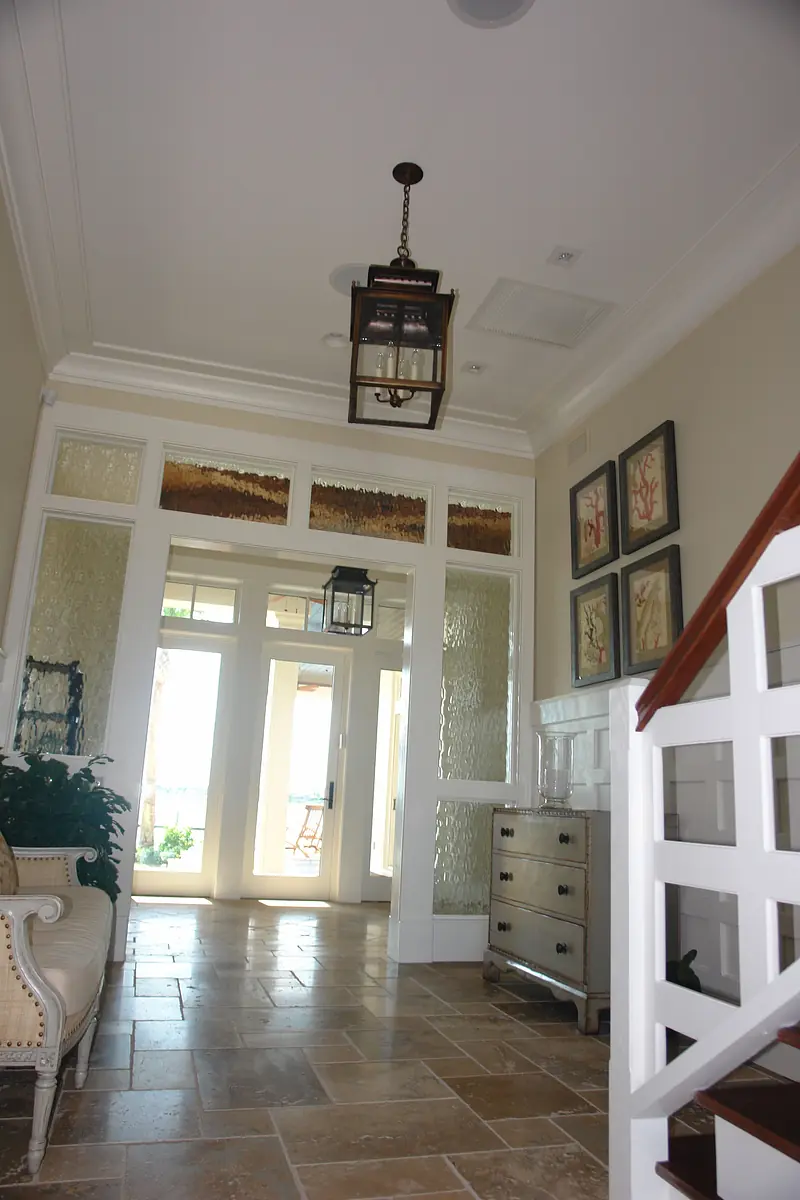 Foyer with staircase, console table, artwork, glass doors, and pendant light.