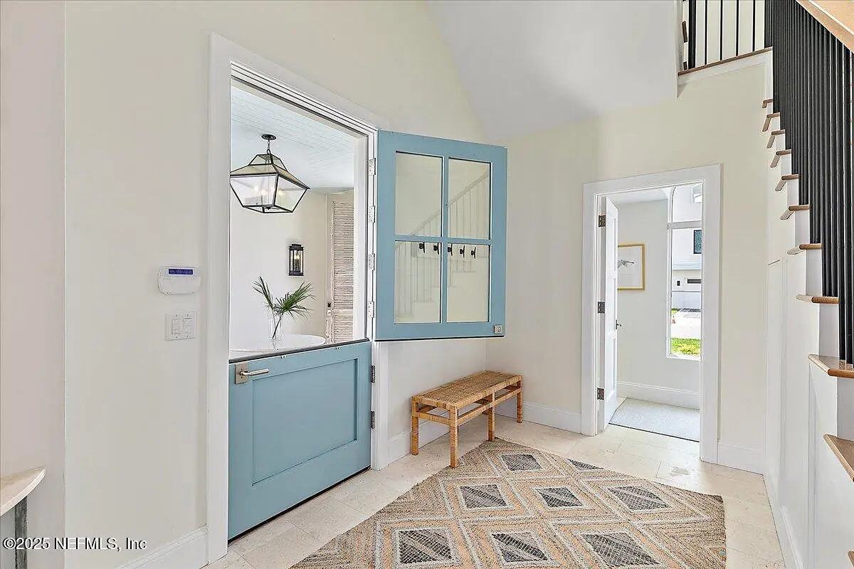 Foyer with blue door, wooden bench, rug, stairway, and tall window for natural light