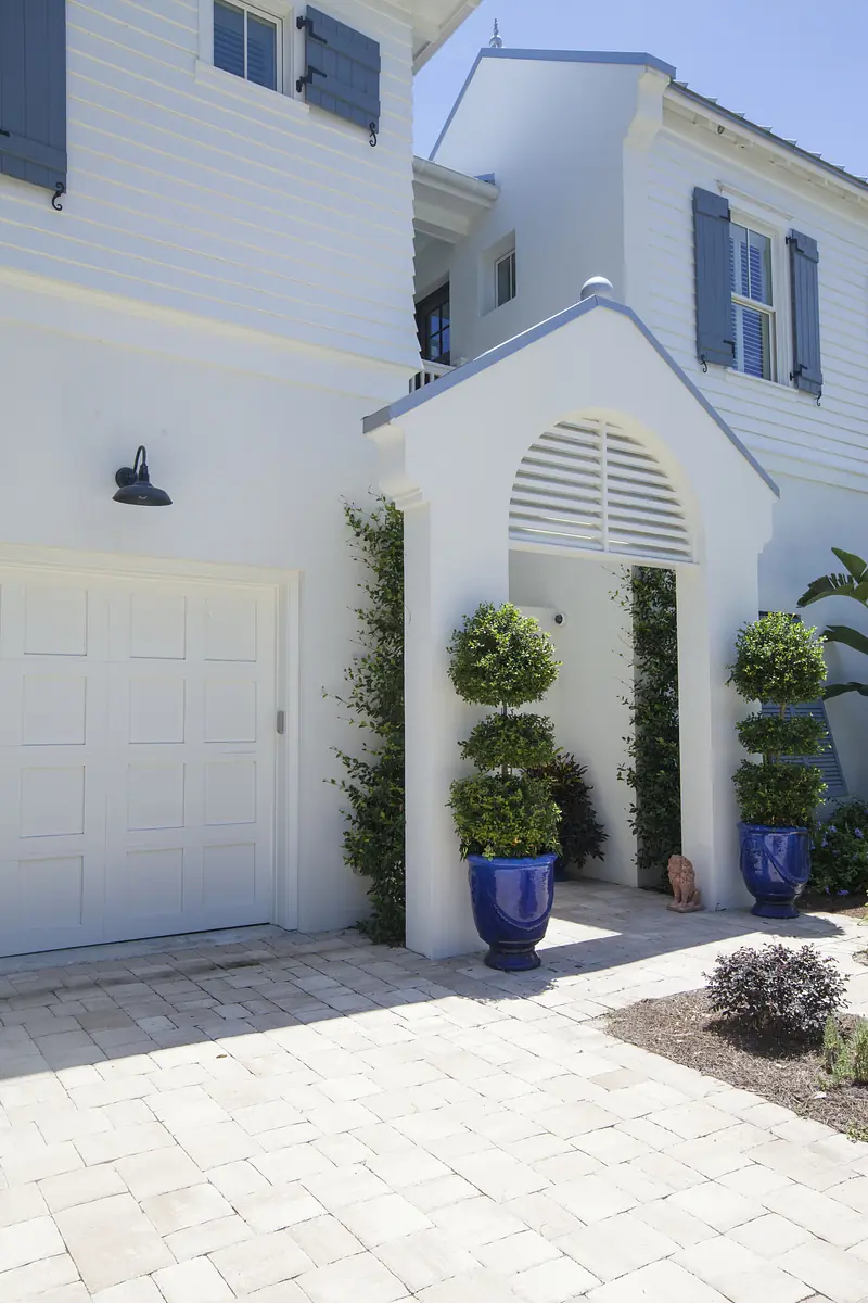 Exterior front with white facade, arched entry, blue planters, and paver walkway.