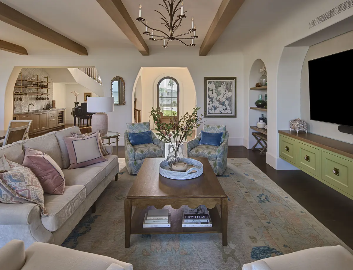 Living room with beige sofa, accent chairs, bronze coffee table, large window, and green built-in cabinets.