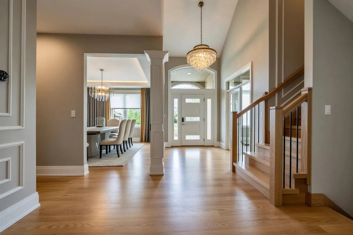 Foyer with wooden floor, chandelier, staircase, and archway to dining area with natural light.