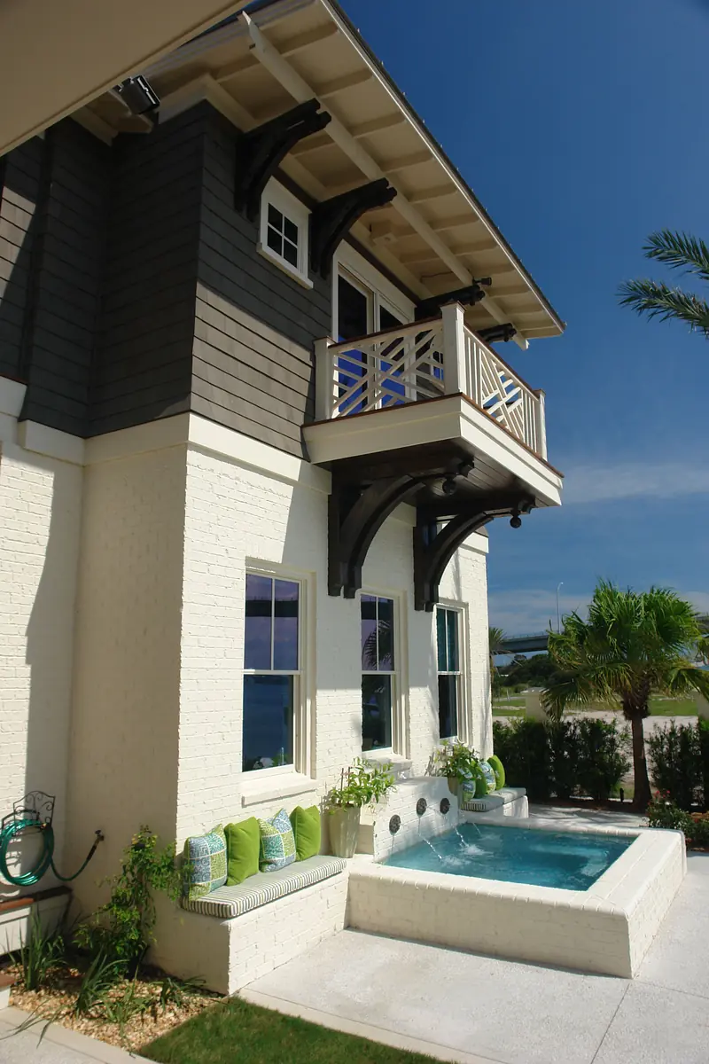 Exterior area with seating, hot tub, windows, balcony, and landscaping.