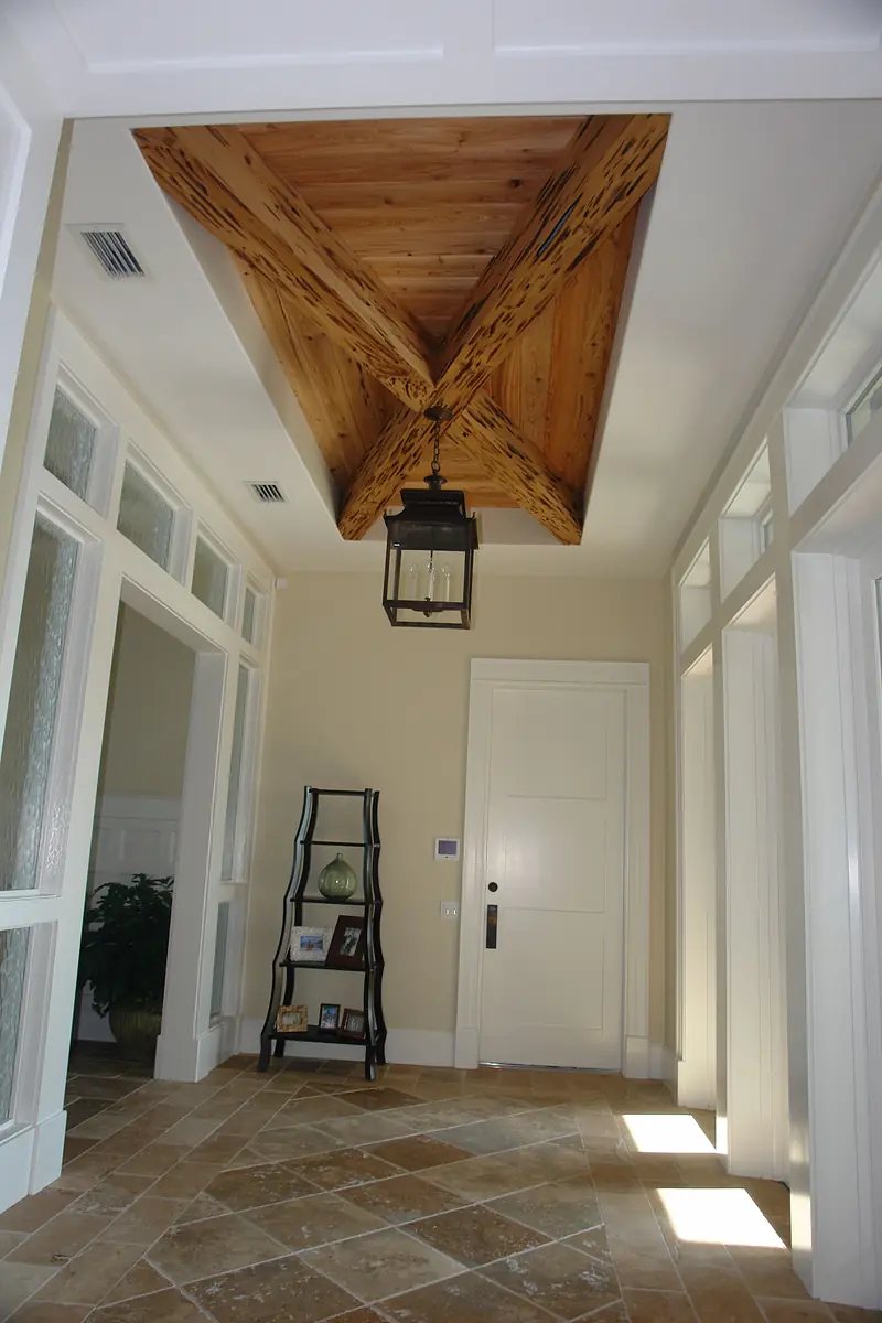Foyer with coffered ceiling, lantern light, decorative shelf, and tile flooring