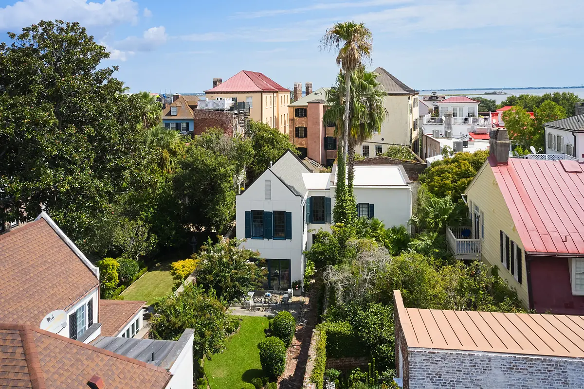 Exterior rear view of a house with landscaped garden, white exterior, blue shutters, and red roof.