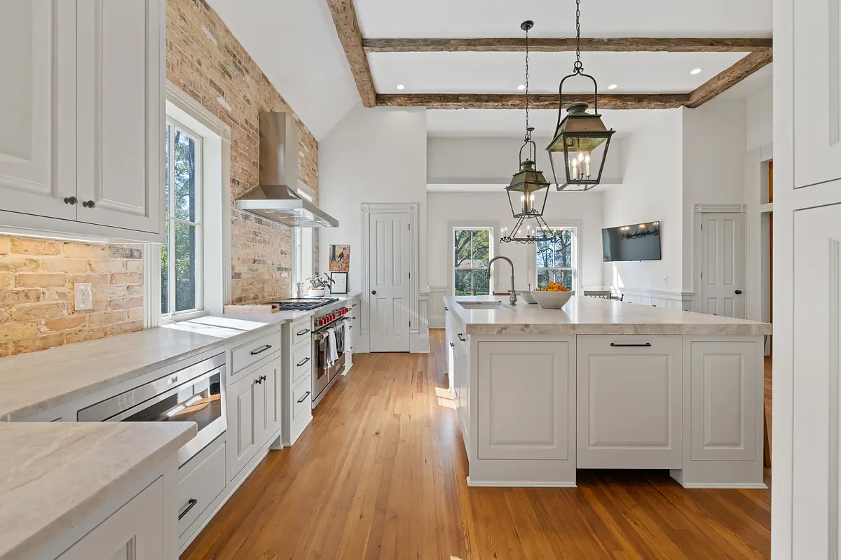 Kitchen with gray cabinetry, marble countertop, stainless steel appliances, central island, and pendant lights