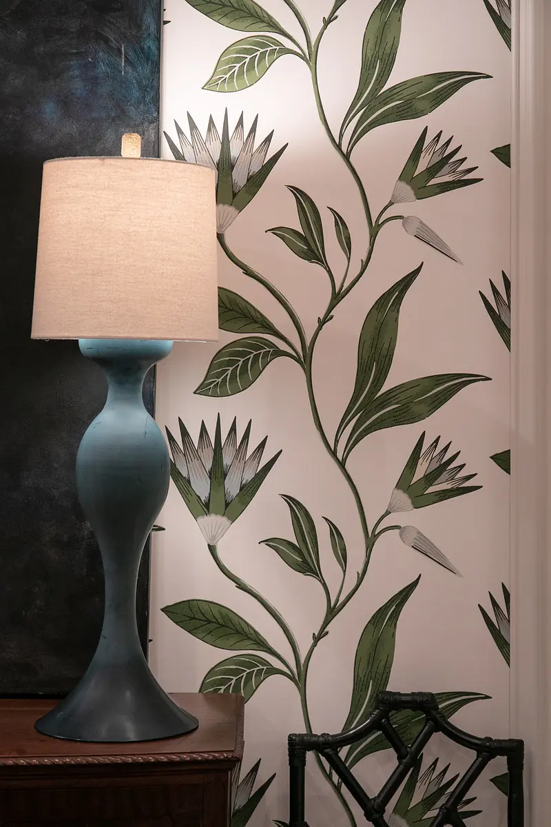 Decorative area with blue lamp, wooden cabinet, and floral wallpaper.