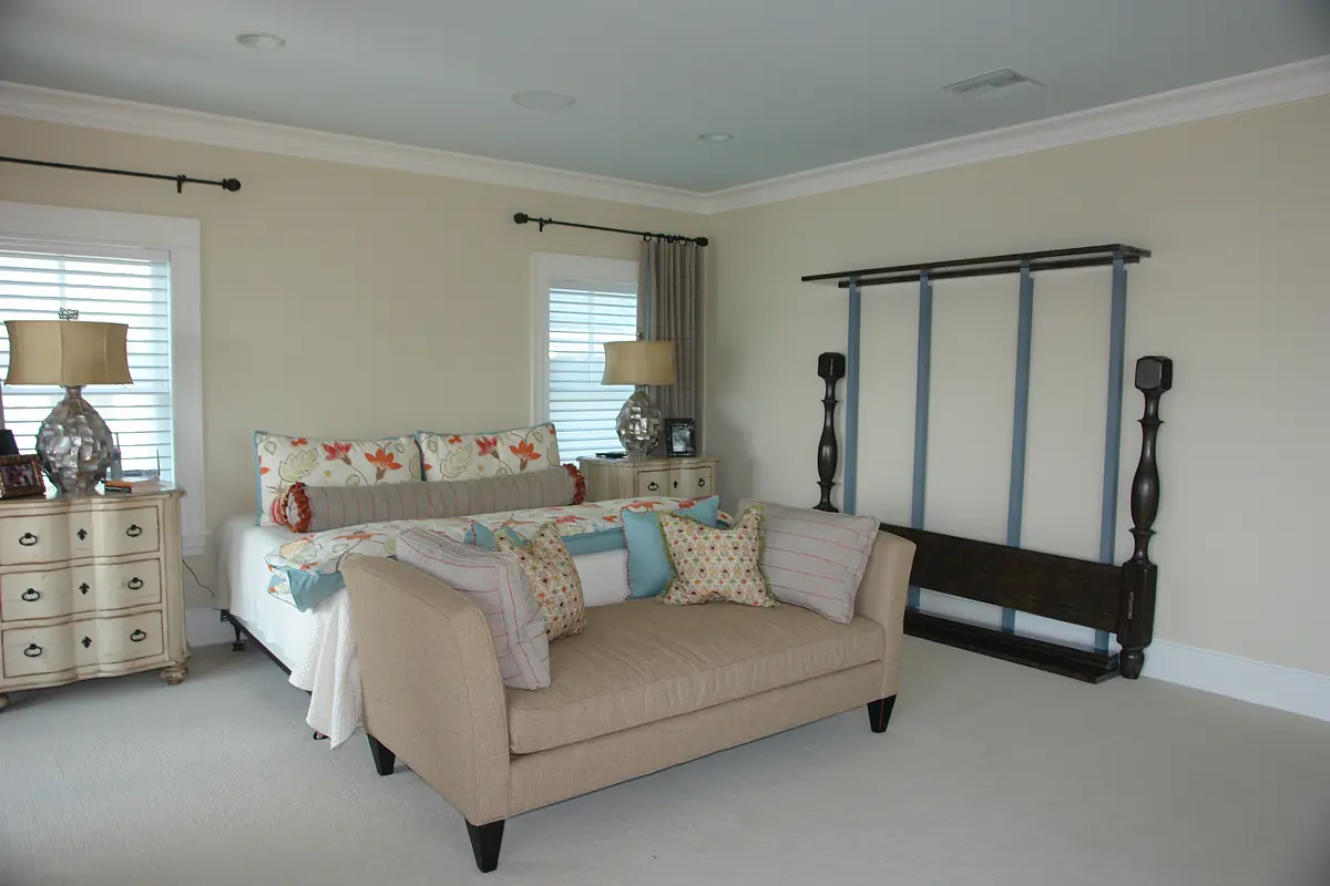 Bedroom with beige sofa, colorful bedding, decorative lamps, and wooden rack.