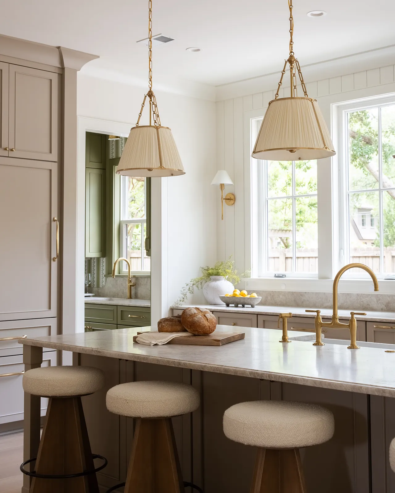 Kitchen with central island, three stools, light countertop, gray cabinets, and large windows.