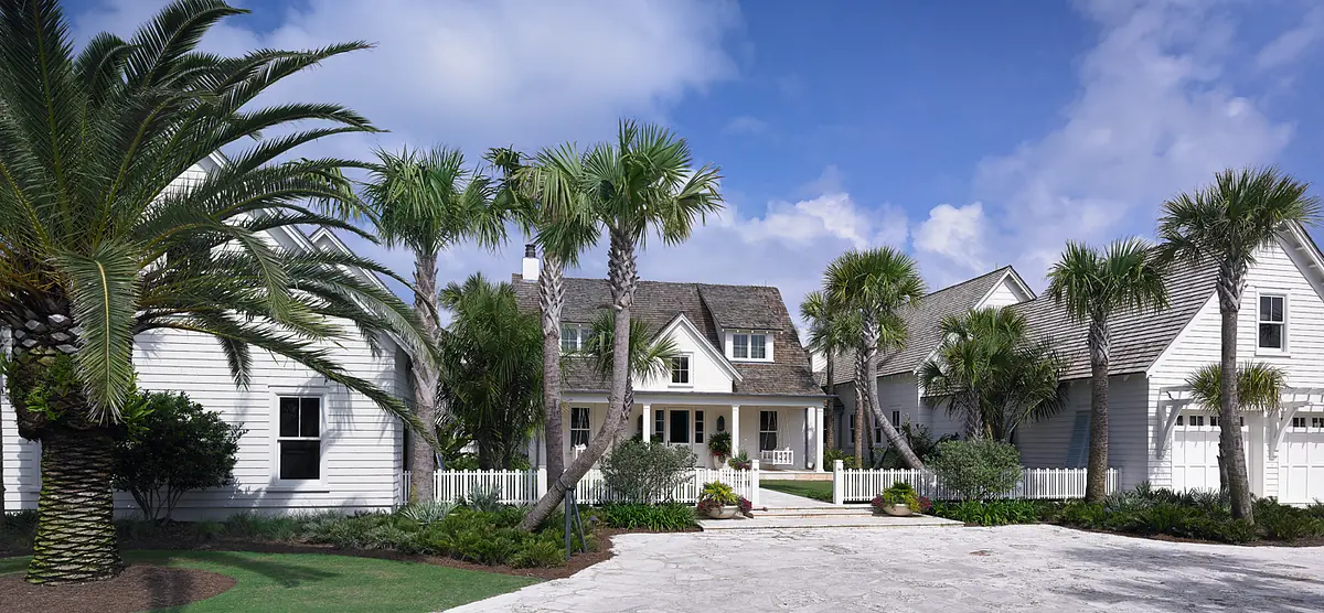 Front exterior view with porch, palm trees, stone driveway, and landscaped greenery