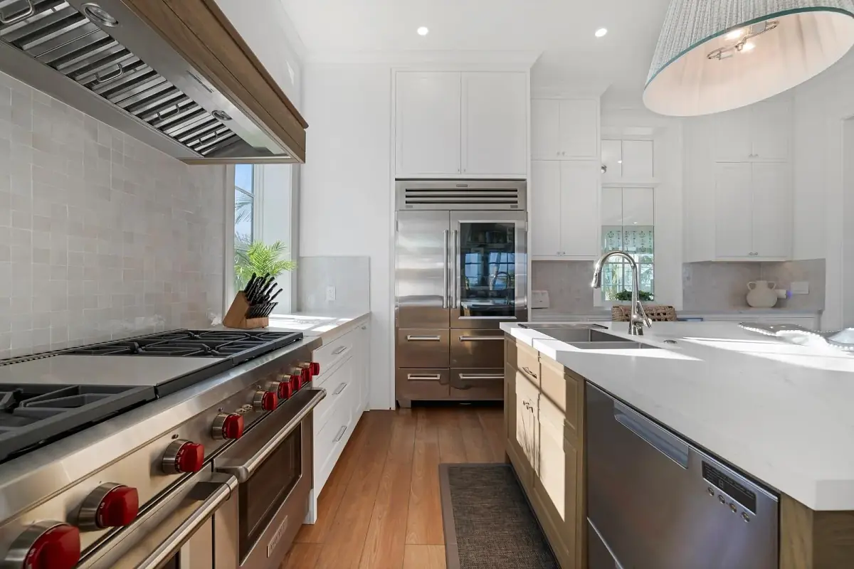 Kitchen with stainless steel appliances, gas range, white cabinets, and wooden floor.