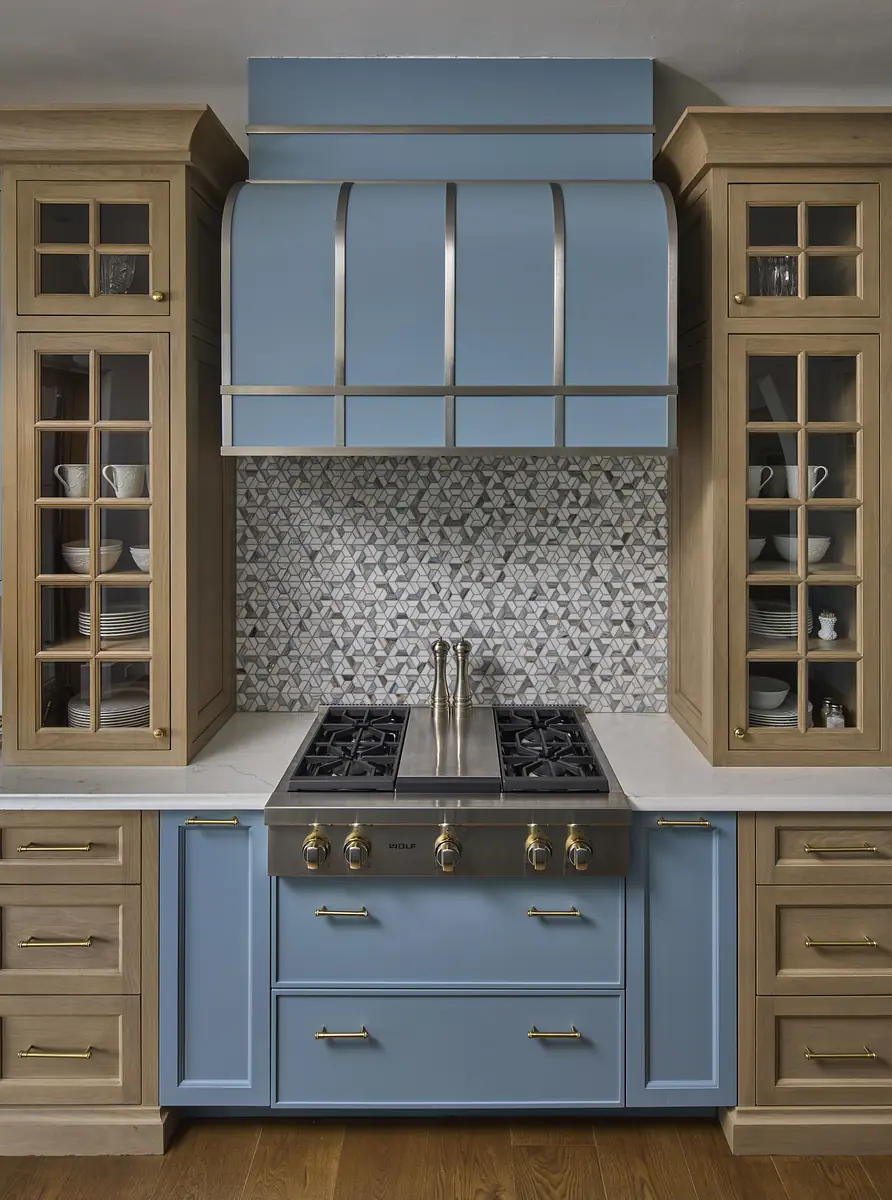 Kitchen with blue cabinetry, stainless steel range hood, gas cooktop, and geometric tile backsplash.