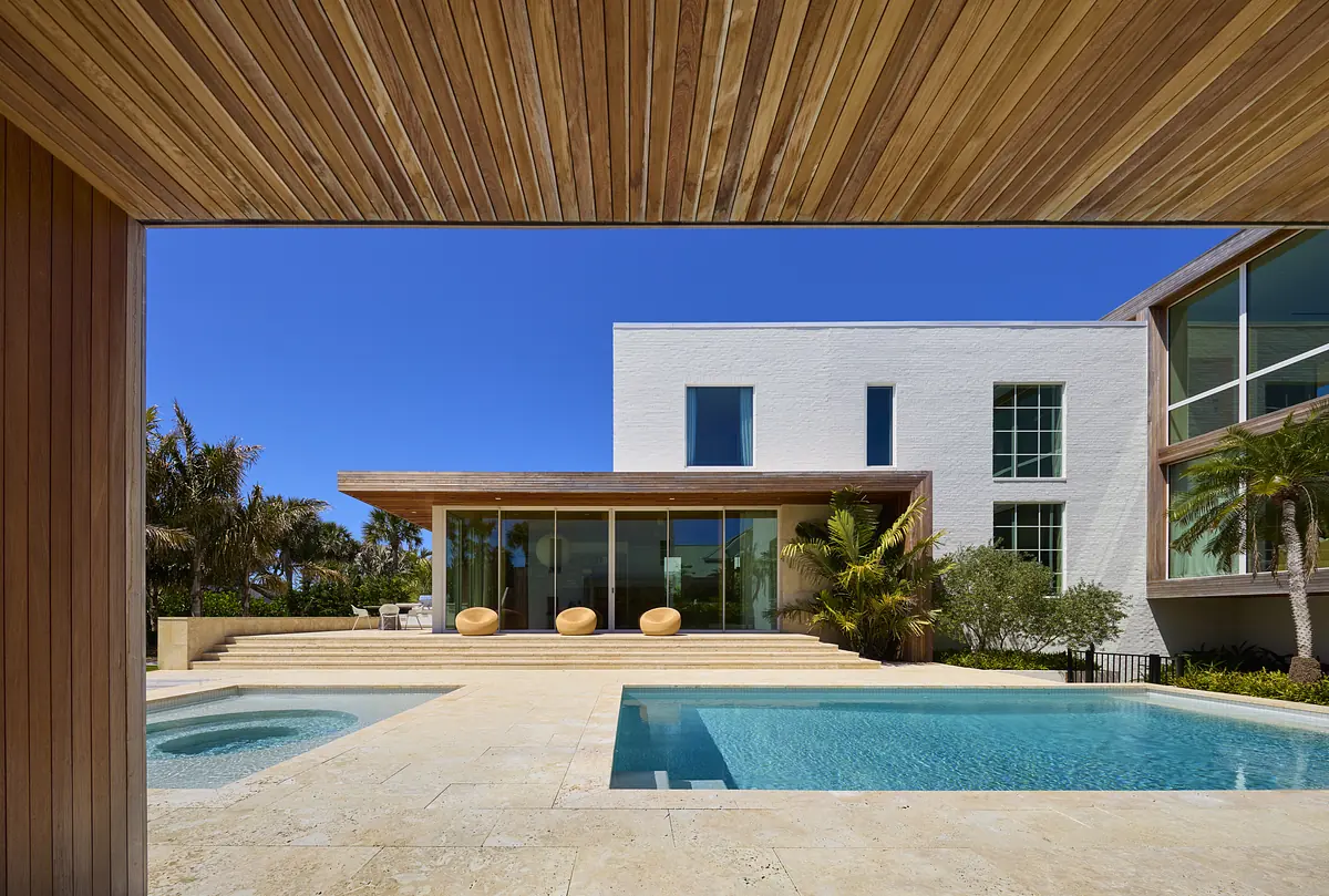 Exterior rear view with swimming pool, spa, terrace, large seating elements, and surrounding vegetation