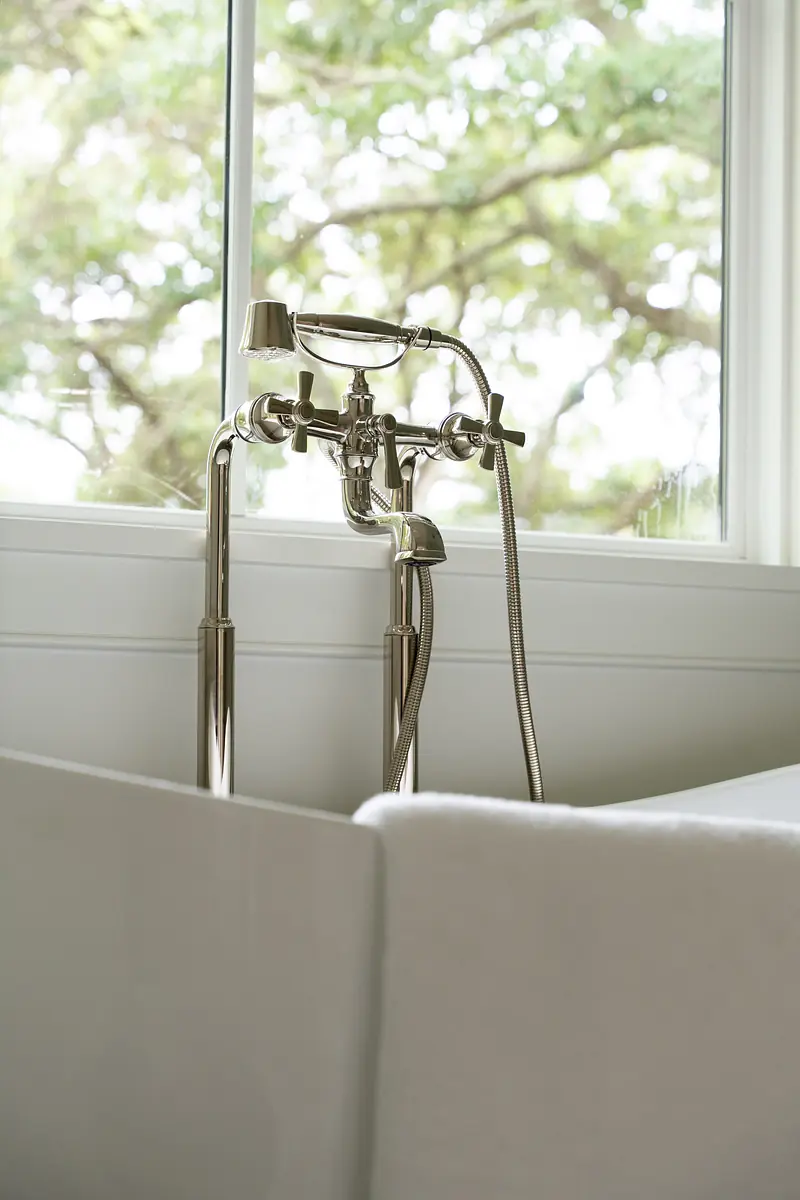 Bathroom with freestanding bathtub, chrome faucet, and large window for natural light.