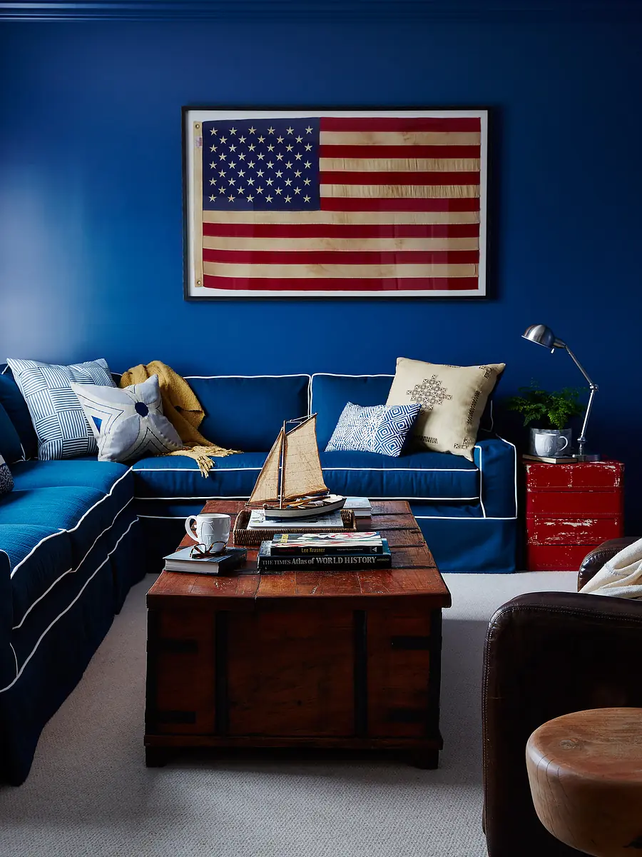 Living room with blue sectional sofa, American flag artwork, wooden coffee table, and red side table