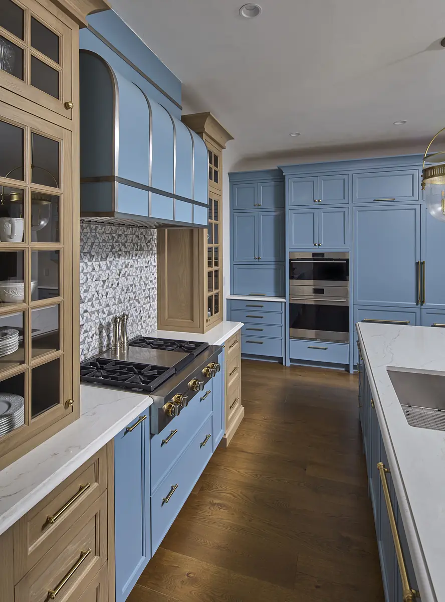 Kitchen with blue cabinetry, white marble countertop, gas stove, built-in oven, and patterned backsplash