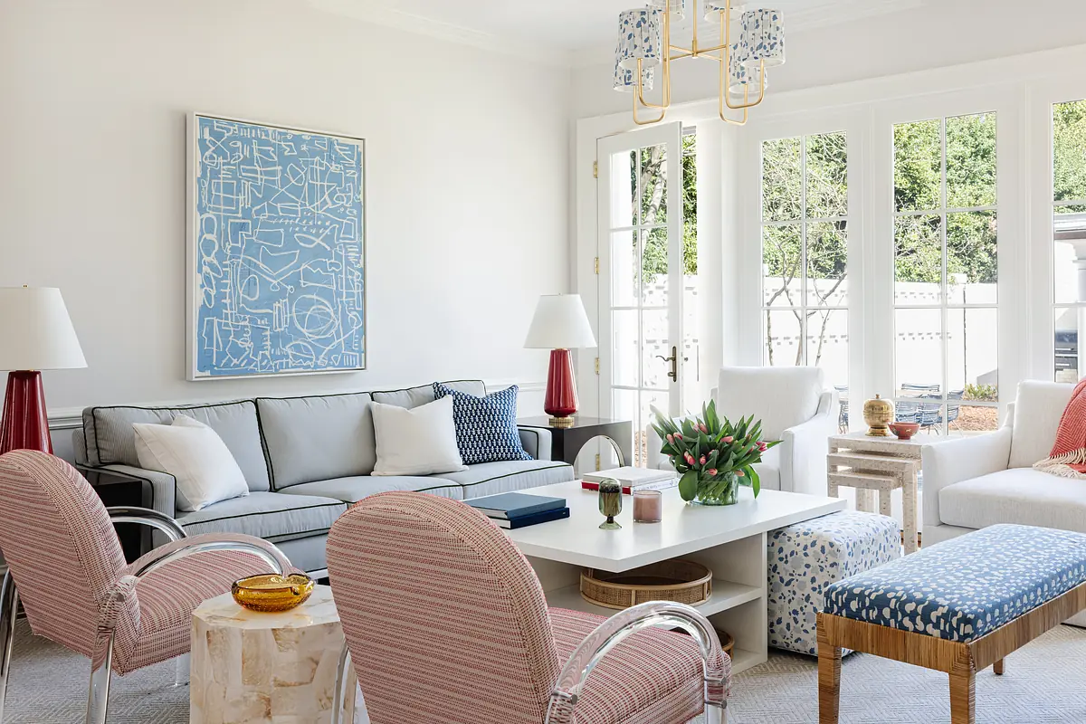 Living room with gray sofa, striped armchairs, white coffee table, and large glass doors for natural light.
