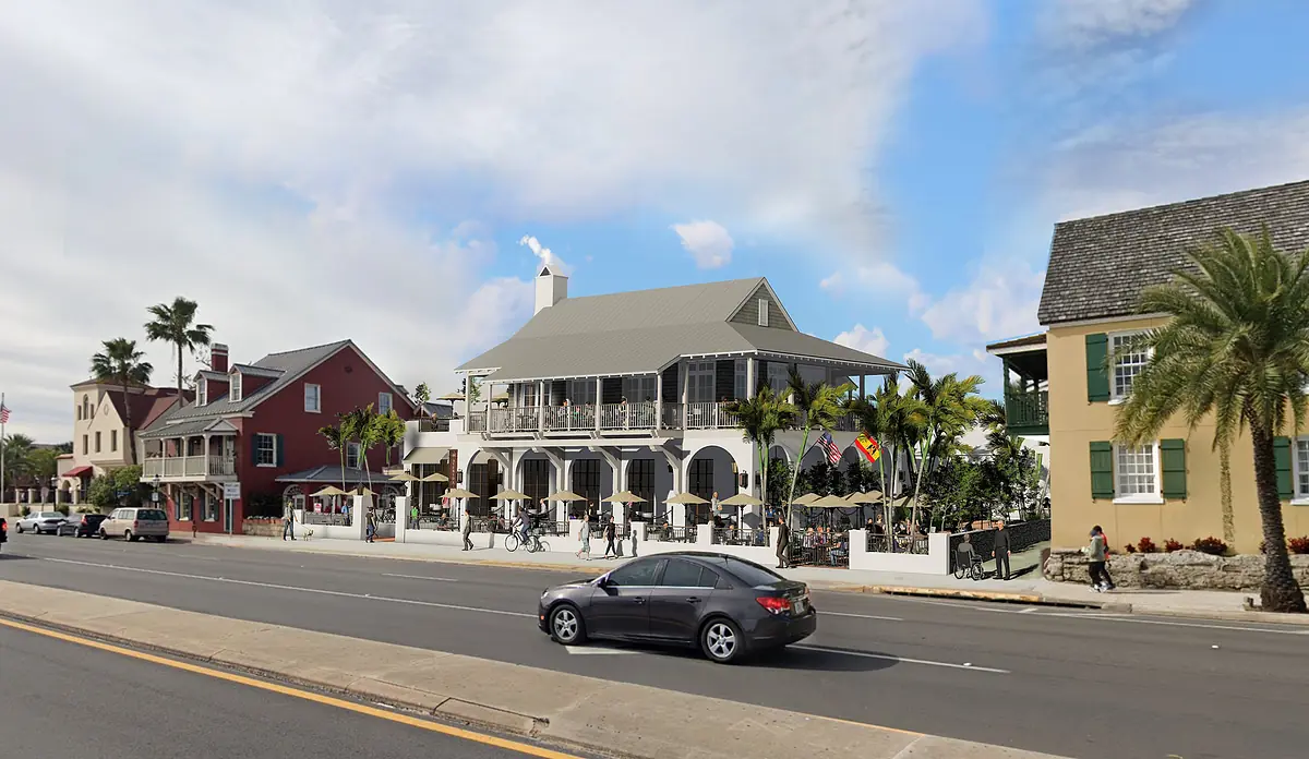 Exterior front view with multi-level building, palm trees, outdoor seating, and adjacent buildings.