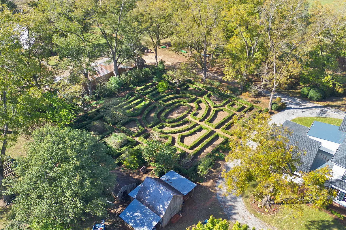 Garden with hedge maze, trees, shrubs, wooden shed, and pathways.