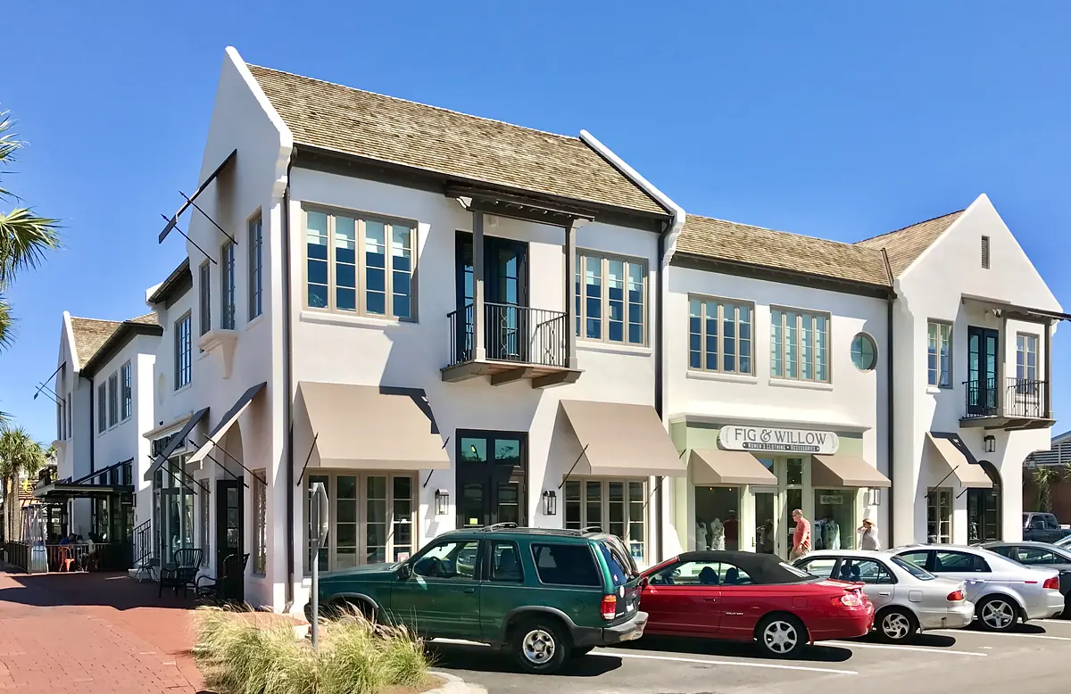 Commercial building facade with blue windows, awnings, and parked cars.