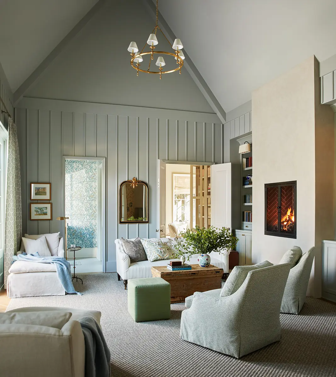 Living room with white sofa, green chair, wood coffee table, fireplace, and light blue paneled walls.