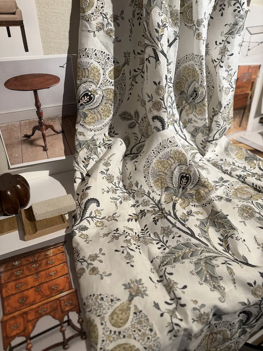 Fabric swatches with floral patterns, a round wooden table, and various furniture samples displayed.