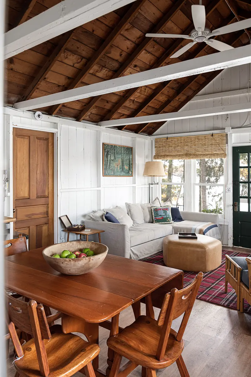 Living room with beige sofa, wooden coffee table, dining table, and exposed beam ceiling.