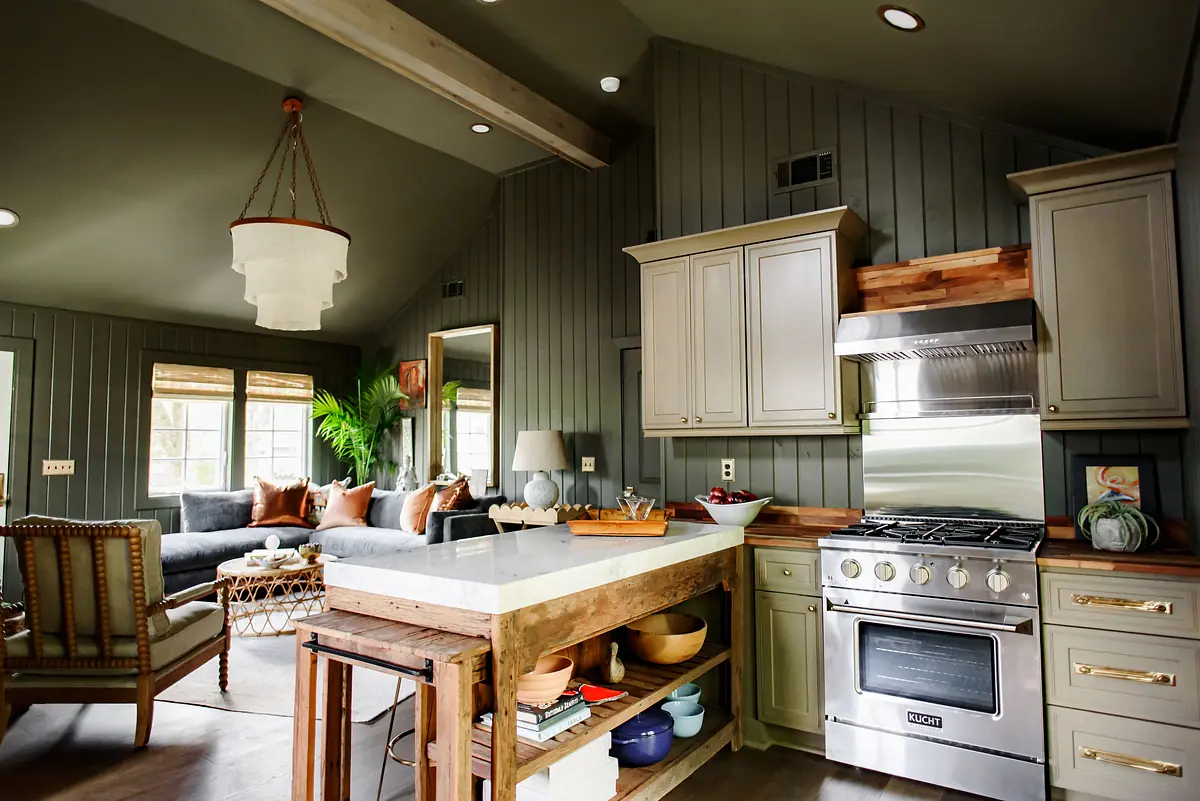 Kitchen featuring gray paneling, white island, stainless steel appliances, and wooden cabinetry.