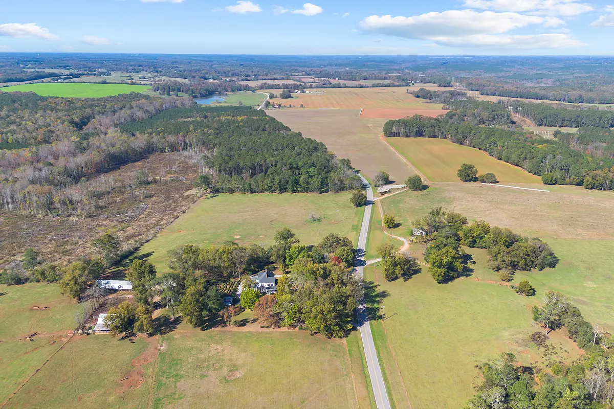 Aerial view of rural landscape with fields, forests, and winding road.