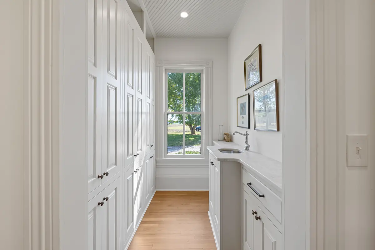 Laundry room with white cabinetry, countertop, stainless steel sink, and a large window
