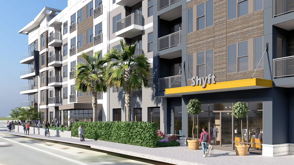 Exterior front of a building with balconies, landscaping, and a sign that reads 'Shyft'.