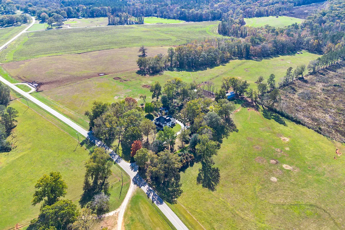 Exterior view of a large property with green lawns, trees, and a winding road.