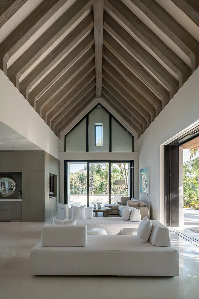 Living room with vaulted ceiling, white sectional sofa, wooden coffee table, large glass doors, and built-in cabinetry.