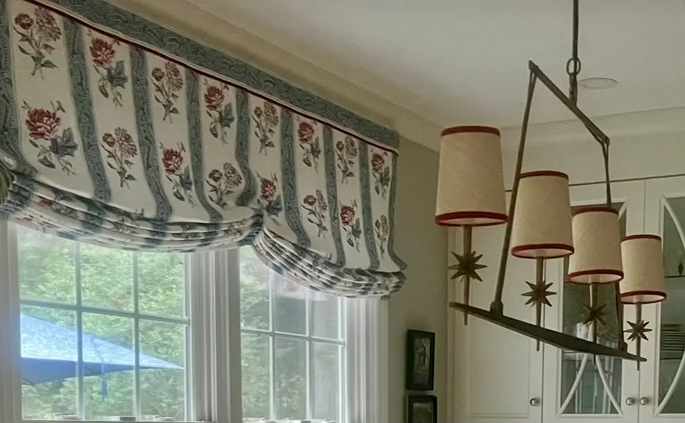 Room with floral window treatments, hanging light fixture, and large windows with outdoor view.