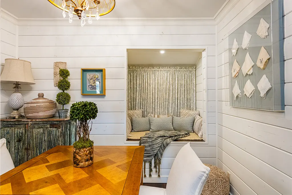 Dining room with wooden table, white chairs, built-in window nook, and decorative wall art.