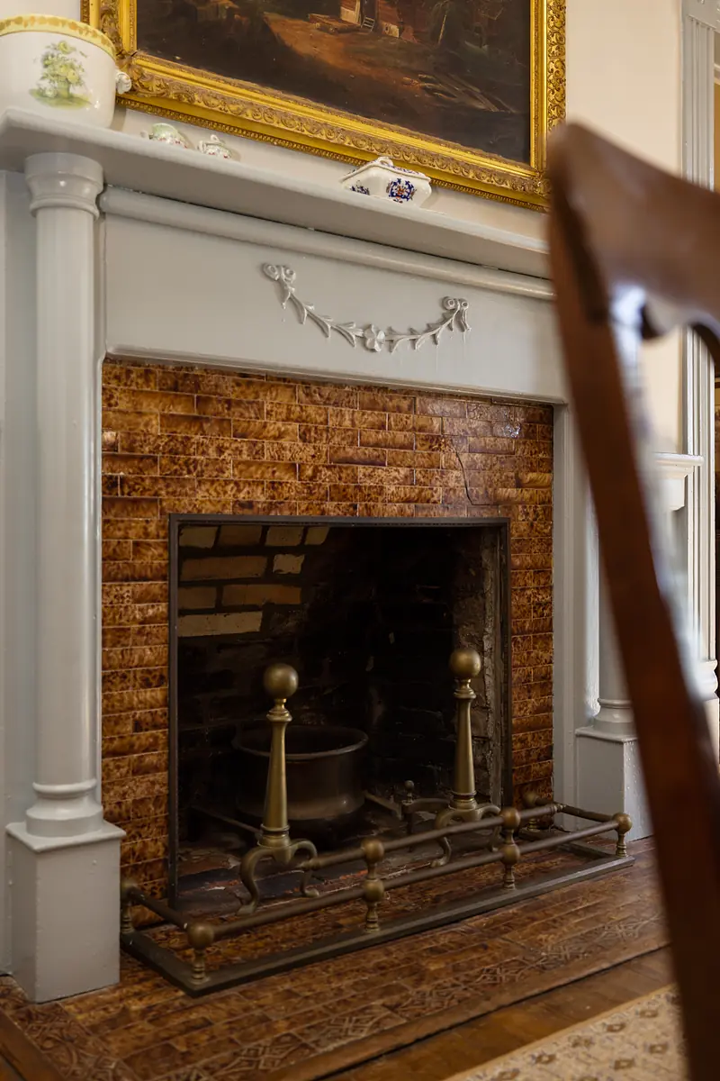 Living room with gray fireplace mantle, brown brick fireplace, gold-framed painting, and decorative bowl.