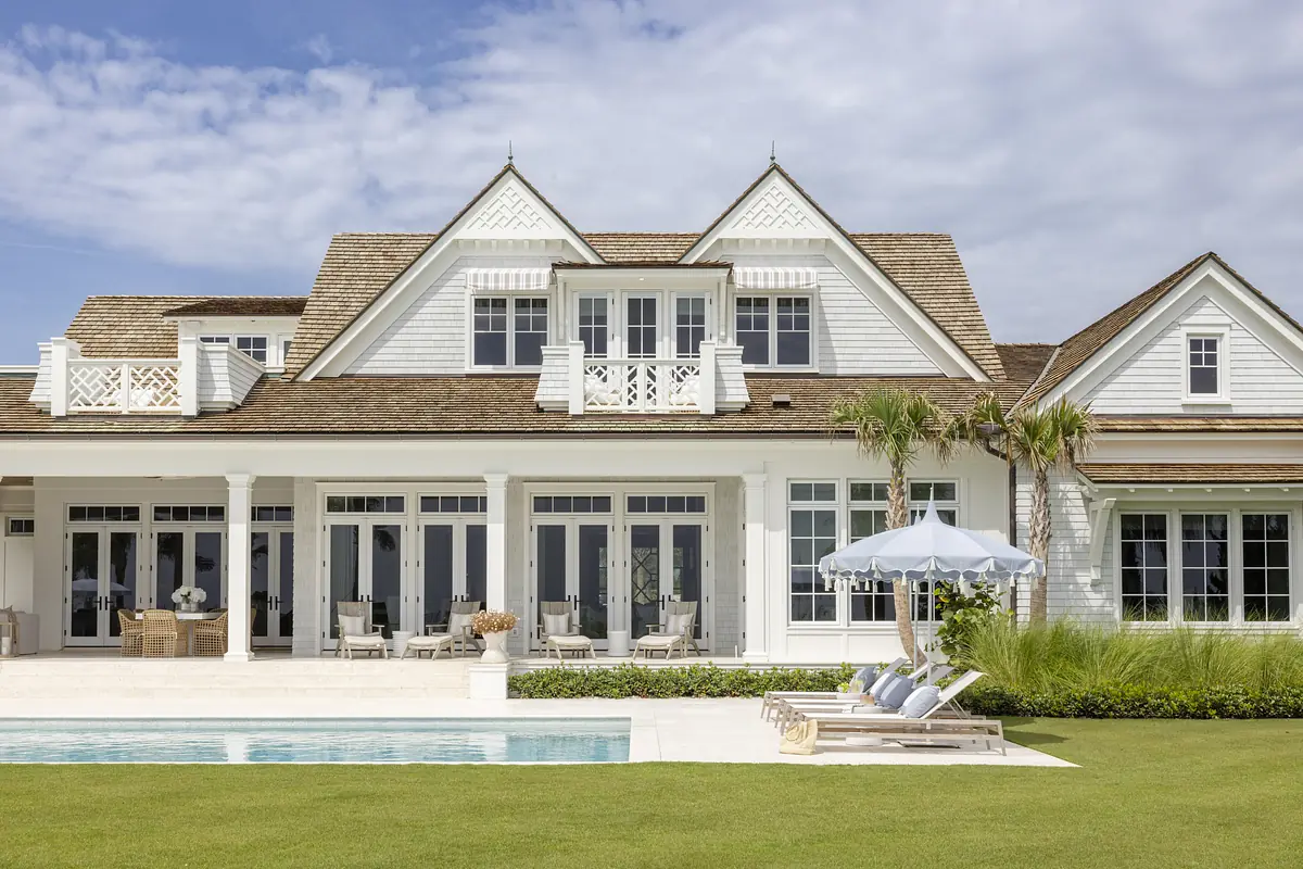 Exterior rear view of a house with swimming pool, lounge chairs, and patio seating.