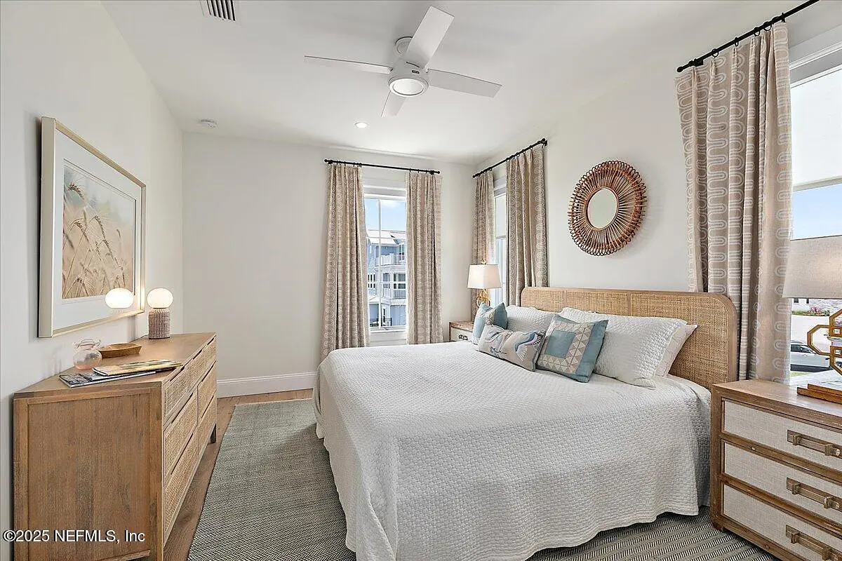 Bedroom with bed, nightstands, dresser, curtains, mirror, artwork, and area rug.