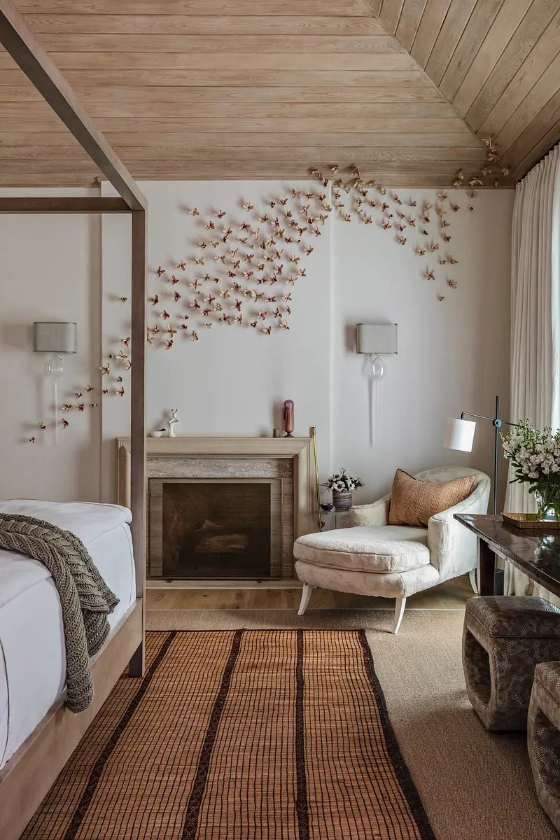 Bedroom with four-poster bed, armchair, fireplace, wall art, and wall sconces