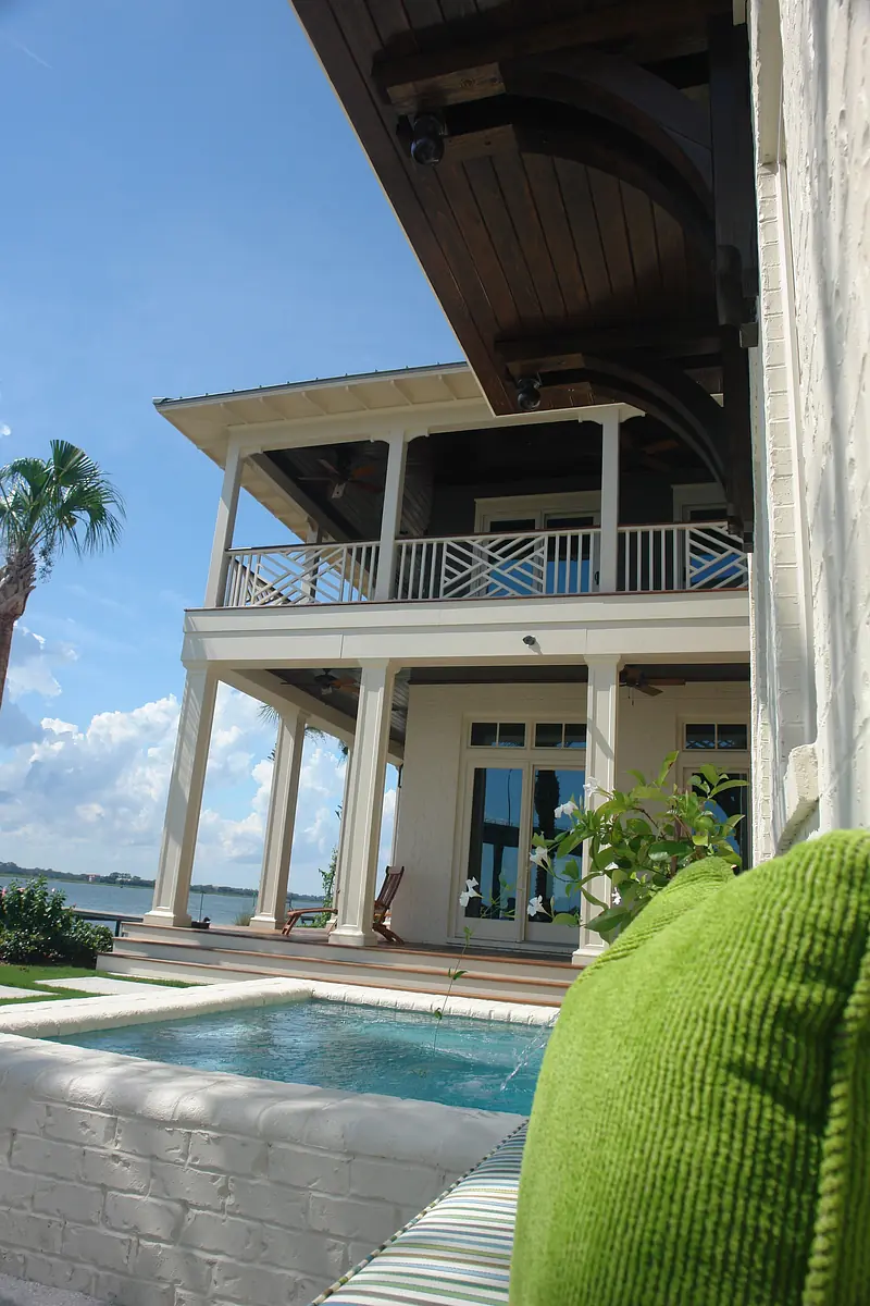 Rear exterior view of a two-level house with large windows, pool, and balcony.