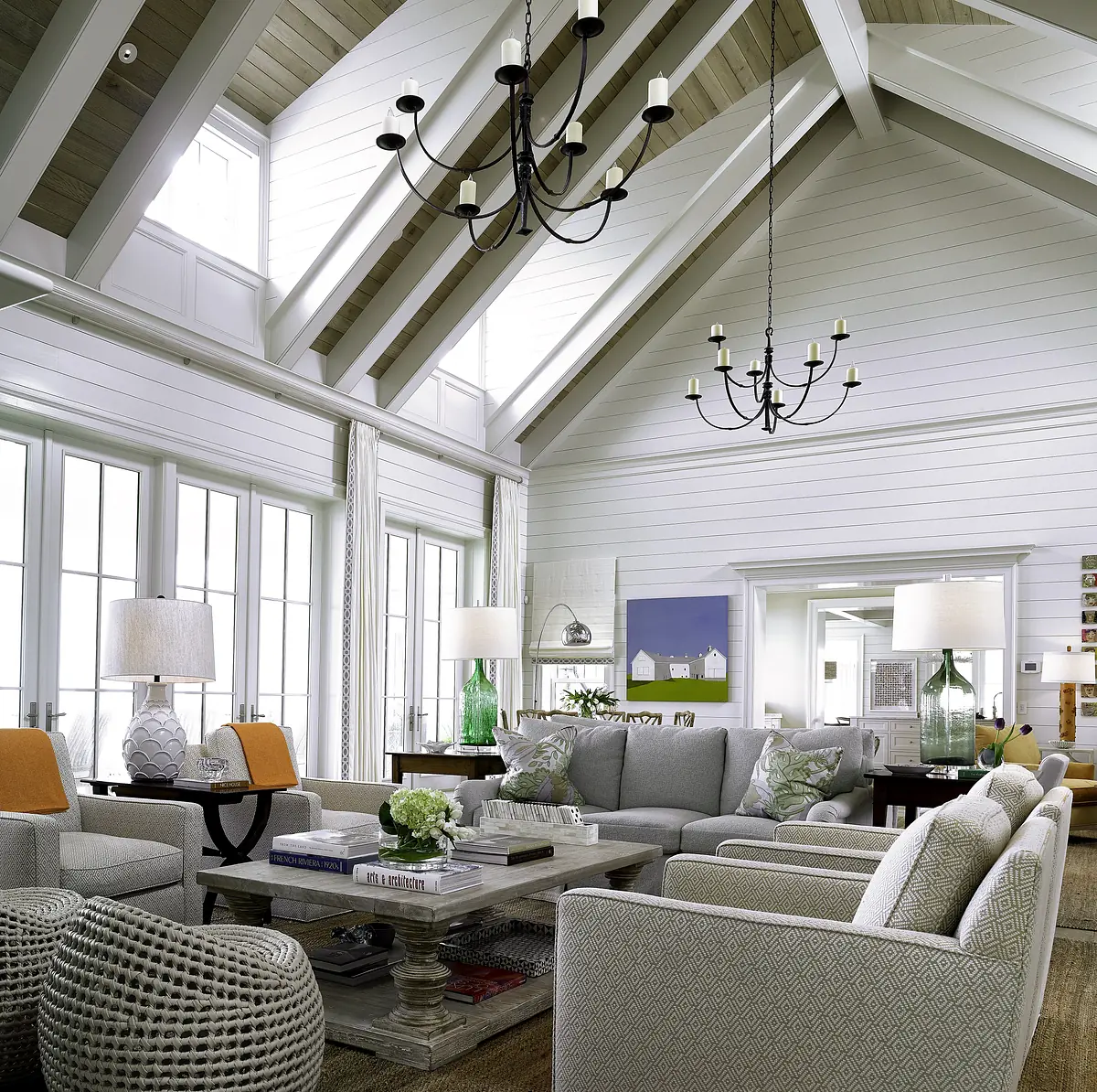 Living room with gray sectional sofa, armchairs, ottomans, coffee table, area rug, and large windows