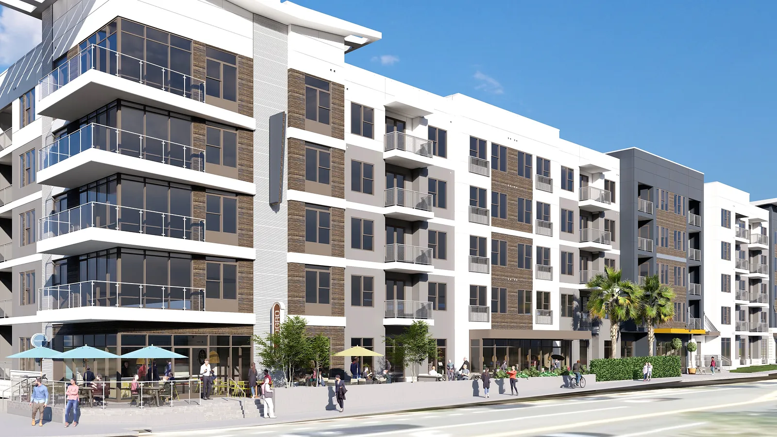 Apartment building with large windows, balconies, outdoor seating, and greenery in front.
