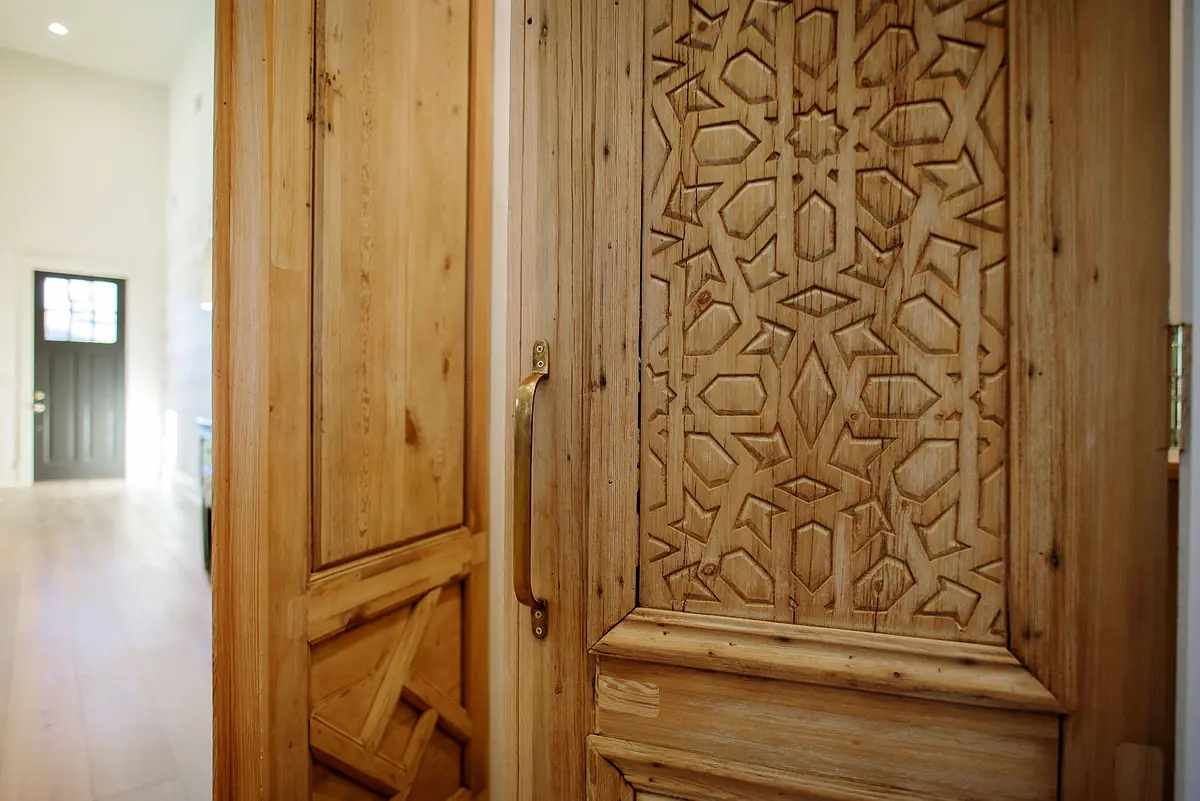 Foyer with carved wooden doors and light hardwood flooring.
