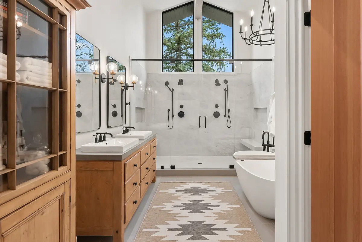 Bathroom with double vanity, freestanding bathtub, walk-in shower, large mirrors, and area rug.