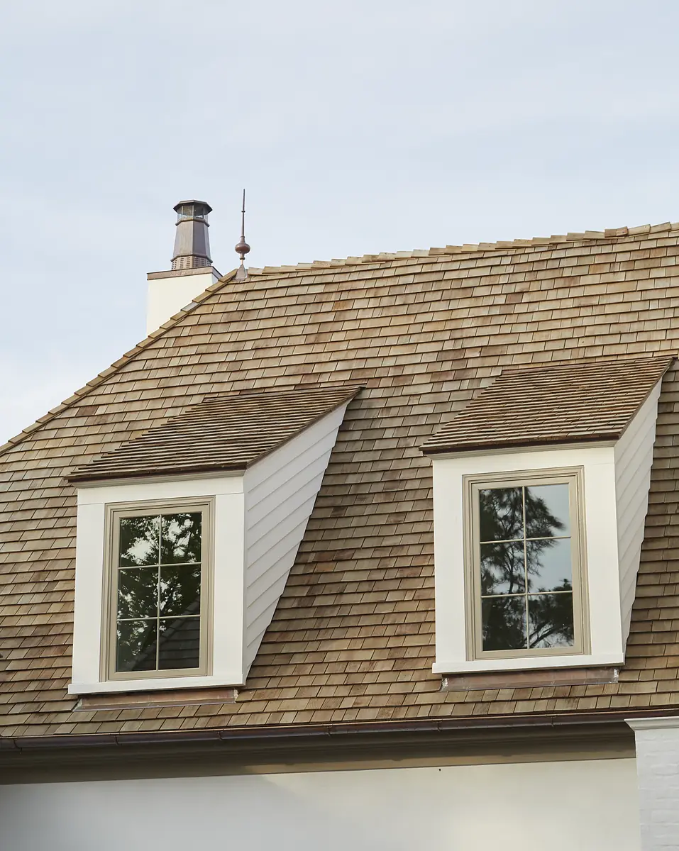 Roof with two dormer windows, wooden shingles, and a chimney.
