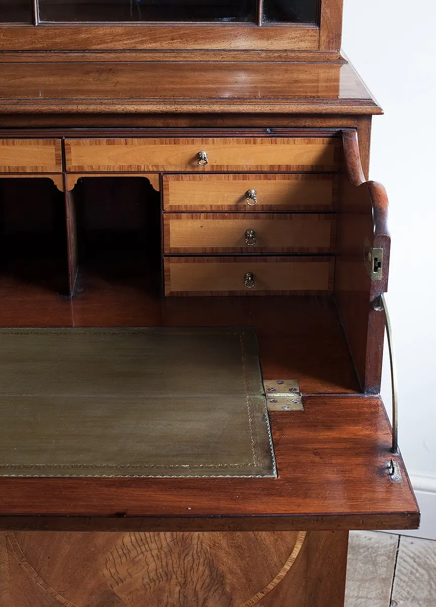 Office with wooden writing desk, leather inlay, and multiple drawers for storage.