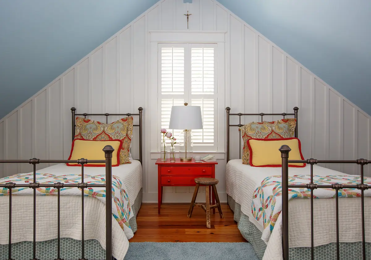 Bedroom with twin beds, red nightstand, blue sloped ceiling, and white shiplap walls.