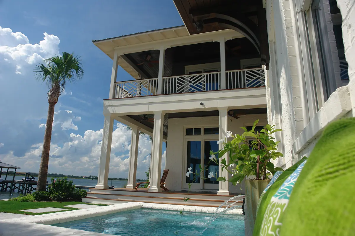 Rear exterior view of house with balcony, swimming pool, and palm tree.