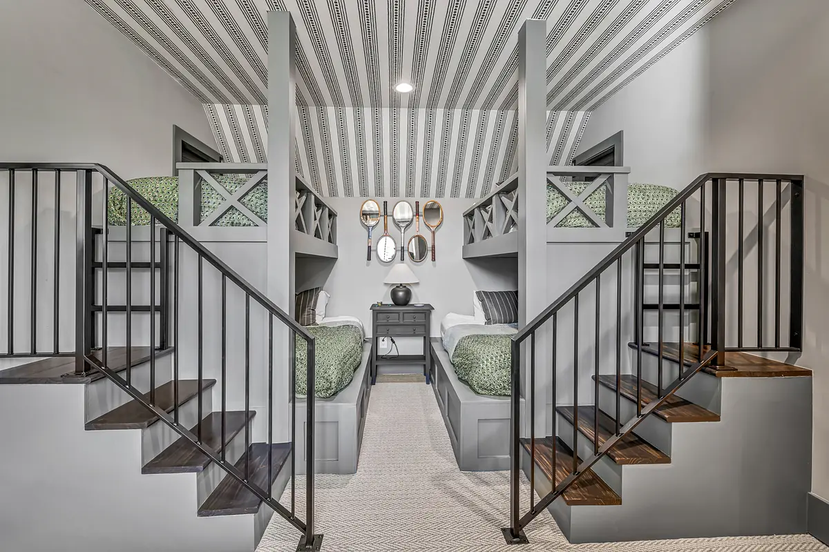 Bedroom with twin bunk beds, green bedding, nightstand, decorative mirrors, and striped ceiling.