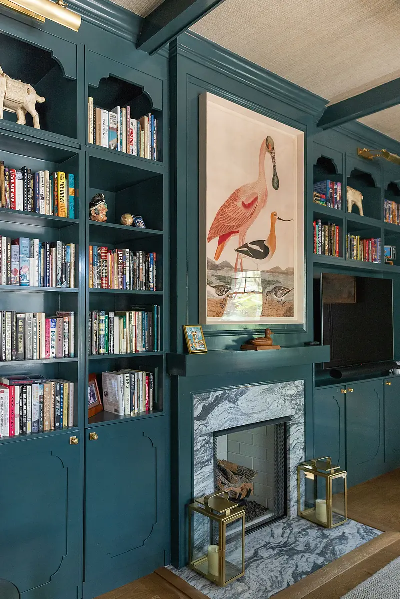 Living room with built-in bookshelves, large artwork, marble fireplace, and mounted television